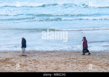 Ein Mann entlang Fistral Beach mit seiner Frau nach Hinter in Newquay in Cornwall. Stockfoto