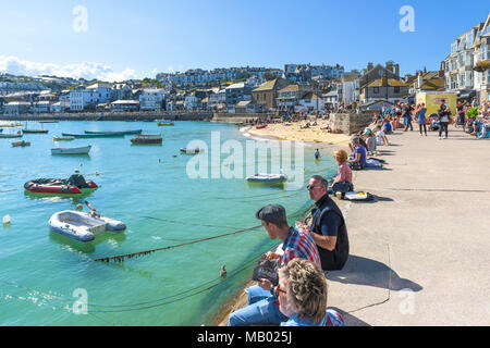 Urlauber entspannen an der Kaimauer im Hafen von St Ives in Cornwall. Stockfoto