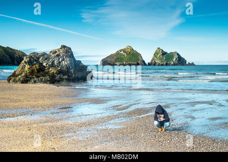 Eine Frau, die Prüfung der Lagerschalen auf Holywell Bay Strand in Cornwall gefunden. Stockfoto