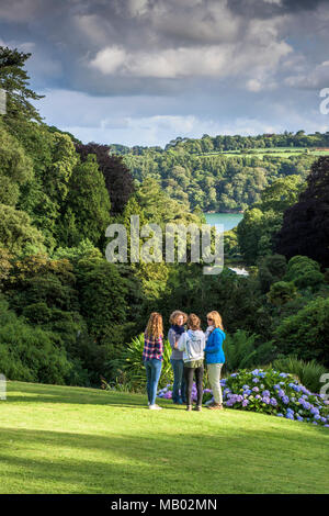 Menschen entspannend, wie sie auf der Wiese in der subtropischen Trebah Garten in Cornwall. Stockfoto