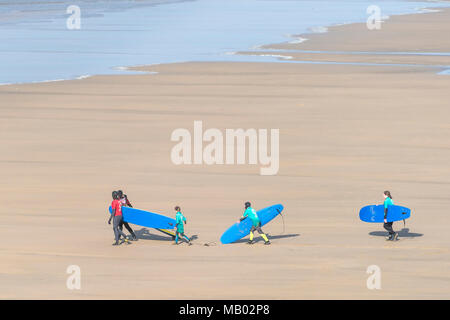 Ausbilder von einer Surfschule Surf Schule und Jugendliche zu Fuß das Meer und die surfbretter auf Fistral Beach in Newquay. Stockfoto