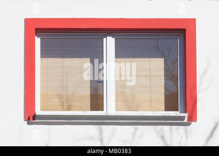 Rot umrandeten Fenster mit Fensterläden auf weißen Hauswand, Bremen, Deutschland, Europa ich rot umrandetes Fenster mit Rolläden heruntergezogenen eine weiss Stockfoto