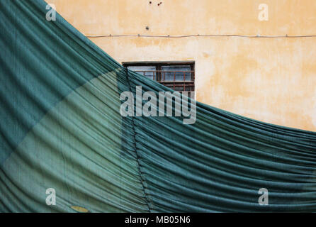 Teilweise Gebäude mesh mit Falten gefallen, schützen das alte Haus mit einem verputzten Wand. Stockfoto
