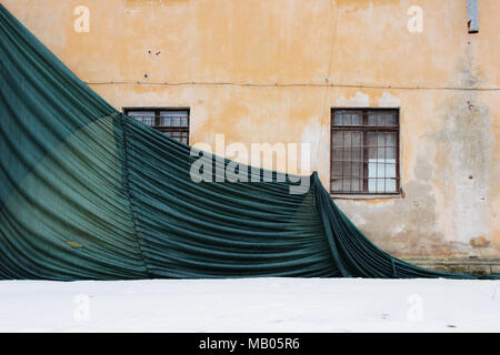 Teilweise Gebäude mesh mit Falten gefallen, schützen das alte Haus mit einem verputzten Wand. Stockfoto