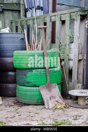 GLASGOW, Schottland - 15. MAI 2013: Eine Schaufel stützt sich auf drei grünen Reifen in einem Glasgow gemeinschaftlichen Garten. Stockfoto