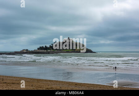Zwei Menschen zu Fuß am Sandstrand in St. Michaels mount in Cornwall in der Nähe von Penzance. Cornish Küstenlandschaft ikonischen Gebäude und Sehenswürdigkeiten Stockfoto