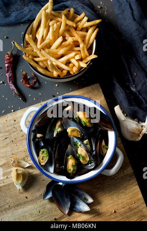 Moules - Pommes frites, Muscheln und Pommes frites, die typisch für Belgien, auf einem rustikalen Holztisch Stockfoto