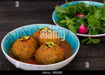 Koofteh Tabrizi große Frikadellen gefüllt mit getrockneten Früchten und Nüssen in Tomaten Kurkuma Brühe eine traditionelle aserbaidschanische und iranischen Gericht serviert in Türkis B Stockfoto