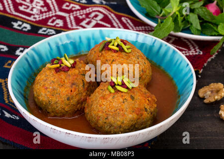 Koofteh Tabrizi große Frikadellen gefüllt mit getrockneten Früchten und Nüssen in Tomaten Kurkuma Brühe eine traditionelle aserbaidschanische und iranischen Gericht serviert in Türkis B Stockfoto