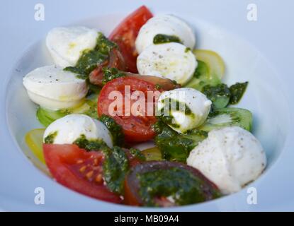 Frische italienische Caprese Salat mit Mozzarella, Tomaten, Basilikum und Pesto auf weiße Platte Stockfoto