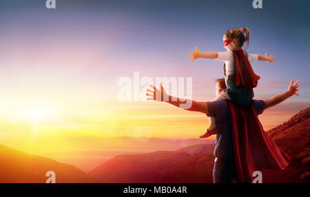 Meine Tochter und ihr Vater gekleidet wie Helden, den Sonnenuntergang zu beobachten. Stockfoto