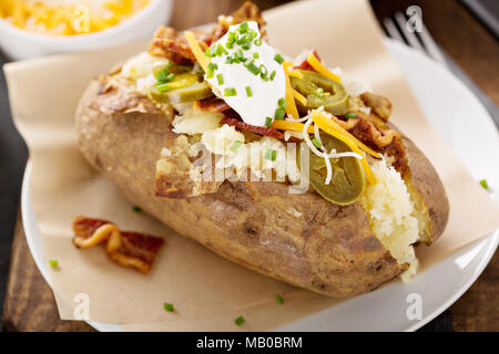 Geladen gebackene Kartoffeln mit Speck, Käse, Sauerrahm und Schnittlauch Stockfoto