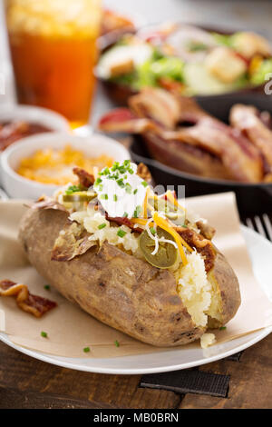 Geladen gebackene Kartoffeln mit Speck, Käse, Sauerrahm und Schnittlauch Stockfoto