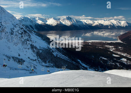 Die Berge der Kenai Halbinsel spiegeln sich in den ruhigen Gewässern des Turnagain Arm als Skifahrer den Aufzug an die Spitze der Run in Alyeska Skigebiet fahren. Stockfoto