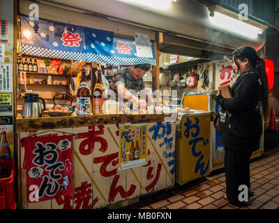 Frau kaufen Essen von einer Garküche, night street, Beppu, Kyushu, Japan Stockfoto