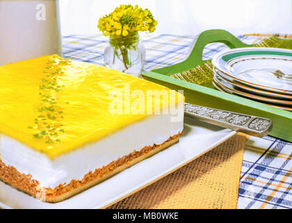 Ganze frische Zitrone mousse Käsekuchen in eine Sommerküche Einstellung auf einem Tisch mit Tellern und Gabeln kopieren Platz im Hintergrund, Stockfoto