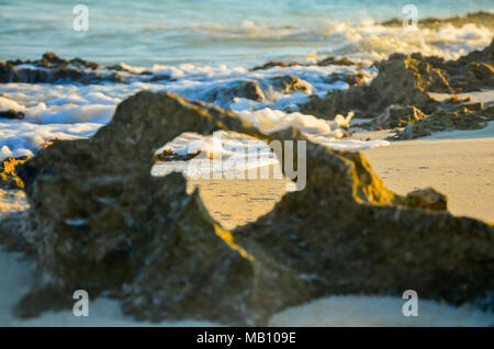 Wellen brechen durch einen natürlichen Rahmen in einem Felsen entlang der Strand von Playa del Carmen, Mexiko gesehen Stockfoto