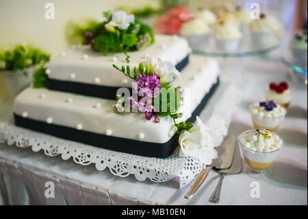 Hochzeitstorte mit Blumen Dekor und weiße Zuckerglasur Stockfoto