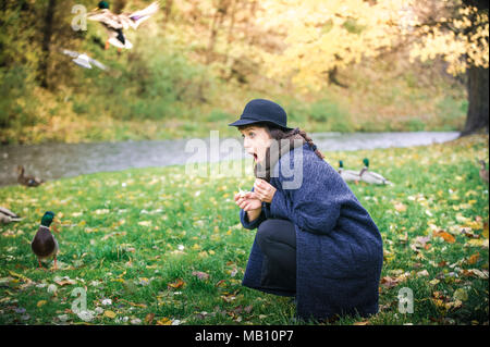 Frau mit Hut füttern wilde Enten Stockfoto