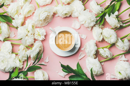 Frühling Morgen Konzept. Flachbild-lay von Tasse Kaffee mit weißen Ranunkeln Blumen über Rosa pastell Hintergrund umgeben, Ansicht von oben Stockfoto