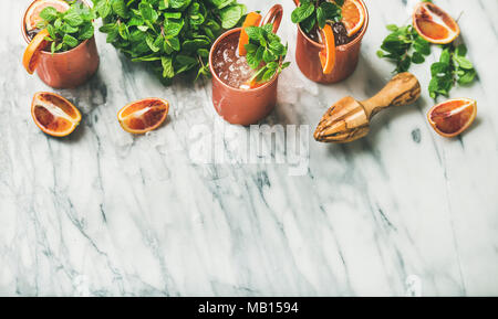 Blutorange Moscow Mule Alkohol Cocktails mit frischer Minze und Eis in Kupfer Becher über weißem Marmor Hintergrund Kopie Raum Stockfoto