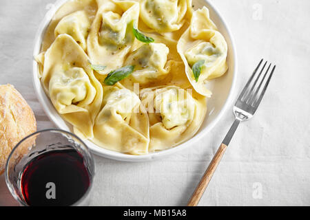 Traditionelle italienische Ravioli mit Ricotta und Spinat, serviert mit einem Glas Rotwein Stockfoto