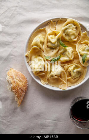 Traditionelle italienische Ravioli mit Ricotta und Spinat, serviert mit einem Glas Rotwein Stockfoto