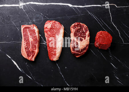 Vielzahl an Raw Black Angus Prime Fleisch steaks Blade auf den Knochen, Roastbeef, Rib Eye, Filet Filet mignon auf dunklem Marmor Background Copy space Stockfoto