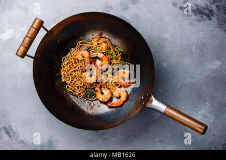 Ramen unter Rühren braten, Nudeln mit Garnelen in wok pfanne auf grauem Beton Hintergrund Stockfoto