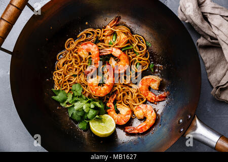 Ramen unter Rühren braten, Nudeln mit Garnelen in wok pfanne auf grauem Beton Hintergrund close-up Stockfoto