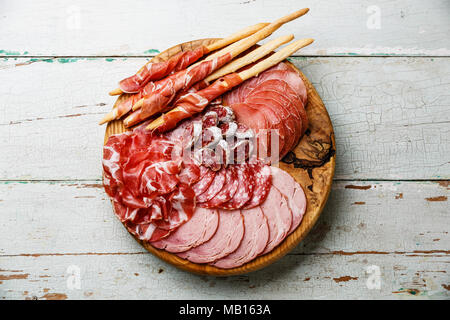 Wurst Platte italienische Snacks essen mit Schinken, Prosciutto, Salami, Schweinekoteletts, Wurst und Grissini Brot klebt auf Holz- Hintergrund Stockfoto