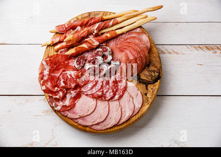 Wurst Platte italienische Snacks essen mit Schinken, Prosciutto, Salami, Schweinekoteletts, Wurst und Grissini Brot klebt auf Holz- Hintergrund Stockfoto