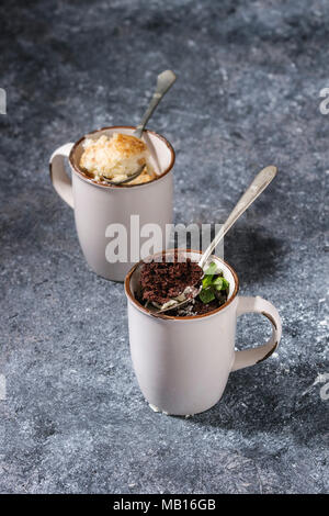 Schokolade und Vanille Karamell Becher Kuchen aus der Mikrowelle mit Löffel über blau Küchentisch. Stockfoto