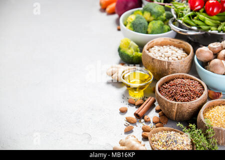 Health Food Konzept mit Hülsenfrüchte, Getreide, Saatgut und ökologischem Gemüse auf grauem Beton Hintergrund, Copyspace Stockfoto