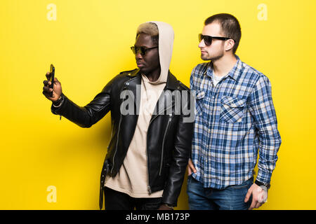 Zwei besten multirassischen Freunde unter selfie mit Handy Kamera auf gelbem Hintergrund. Stockfoto