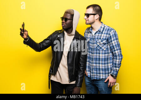 Zwei besten multirassischen Freunde unter selfie mit Handy Kamera auf gelbem Hintergrund. Stockfoto