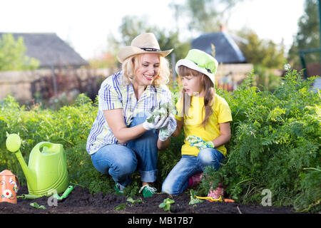 Gartenarbeit, Pflanzen - Mutter mit Kind anlage Erdbeere Sämlinge in Garden Bed Stockfoto