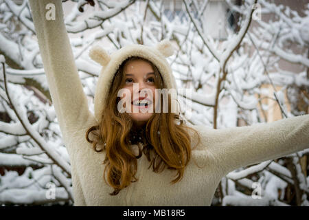 Portrait von niedlichen Happy teenage Mädchen im Schnee. Winter Thema. Closeup schöne jugendlich Mädchen, lange Haare, weißes Fell, lächelnd im Schnee. Stockfoto