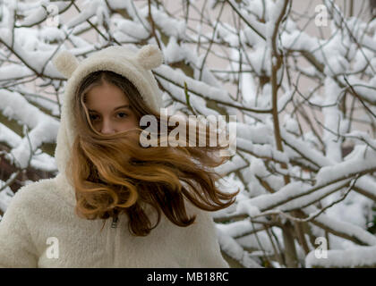 Portrait von schönes junges Mädchen im Schnee. Langes Haar weht im Wind. Winter Thema. Stockfoto