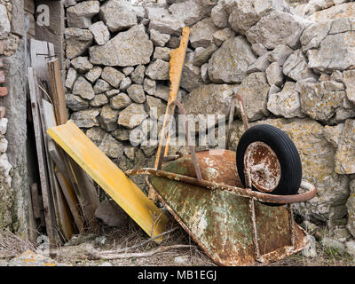 Alten rostigen Schubkarre auf dem Boden liegend vor Steinmauer in Lubenice, Cres Kroatien Stockfoto