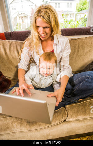 30 ish Mutter und ihrem Baby Boy Spielen zusammen mit einem Laptop. Stockfoto