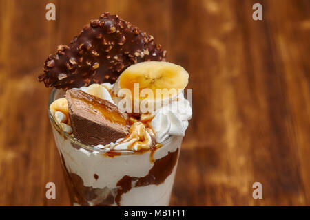 Eis Schokolade Cocktail in Glas mit Sirup, Banane, Süßigkeiten und andere Leckereien, Nahaufnahme Stockfoto