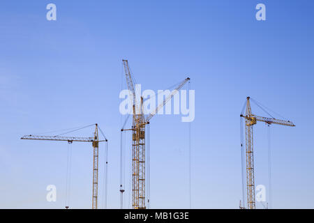 Vorderansicht von drei Kranichen auf hellblauem Himmel Hintergrund. Baustelle. Stockfoto