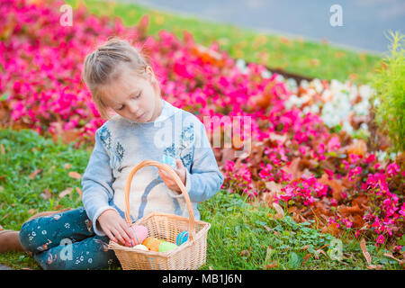 Kleines Kind mit Ostereier in busket auf Ostern im Gras sitzen Stockfoto