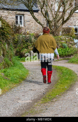 Eine Frau oder Dame zu Fuß an einem Feldweg in Cornwall, in einem alten Bauernhaus aus Stein das Tragen der roten Stiefel und Trendy modische Land Kleidung. Stockfoto