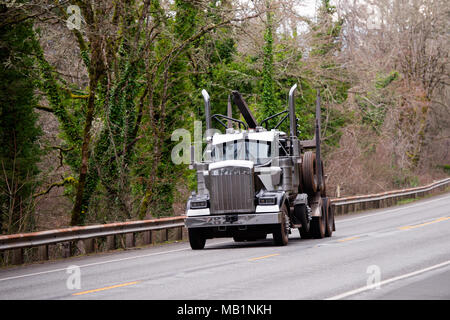 Big Rig mächtigen amerikanischen Motorhaube halb Lkw für den Transport von langen Schnittholz Rundholz bewegt sich auf dem Ort der Verladung mit einem speziellen Anhänger eingetaucht in ein Stockfoto