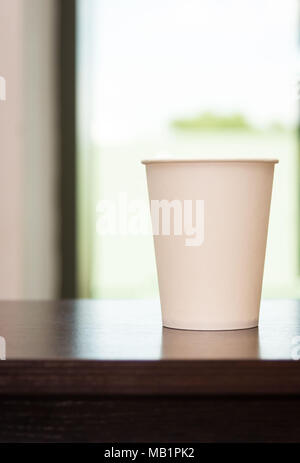 Weiße Tasse steht auf einem Holztisch Stockfoto