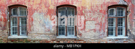 Die drei faulen gebogene Fenster in der Roten Wand eines zerstörten alten Backsteinhaus. Panoramablick auf die Collage aus mehreren Outdoor street Fotos Stockfoto