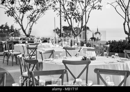 Die Schwarzen und Weißen der Hochzeit Dinner Table Setup, mit dem Modernen klappbarer Liegestühle. Das leere Glas und Platz auf dem Tisch, die Kerze ein Stockfoto
