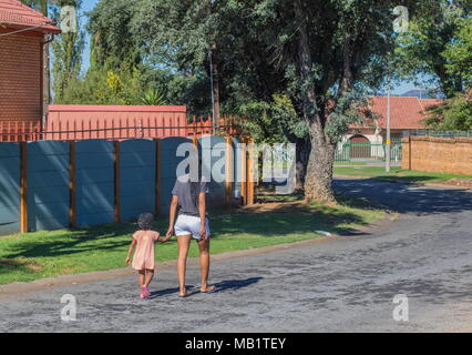 Johannesburg, Südafrika - Unbekannter afrikanische Mutter und Kind in der traditionellen dreadlocks Frisuren zu Fuß eine Wohnstraße in der Stadt Stockfoto